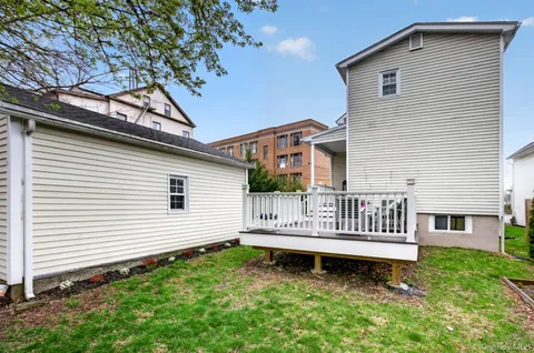 a white house that has a small yard and large trees