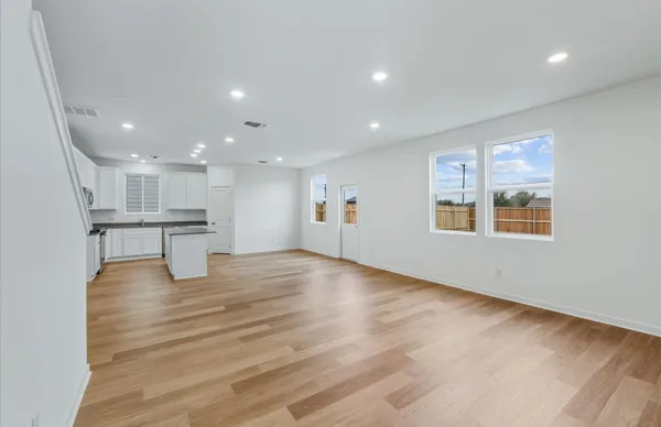 a view of empty room with wooden floor and windows
