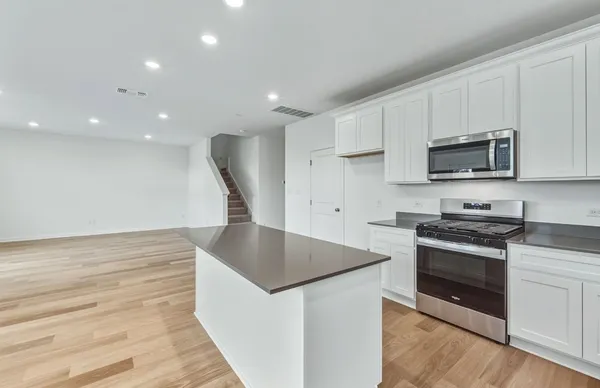 a kitchen with stainless steel appliances kitchen island granite countertop a stove a sink and a microwave