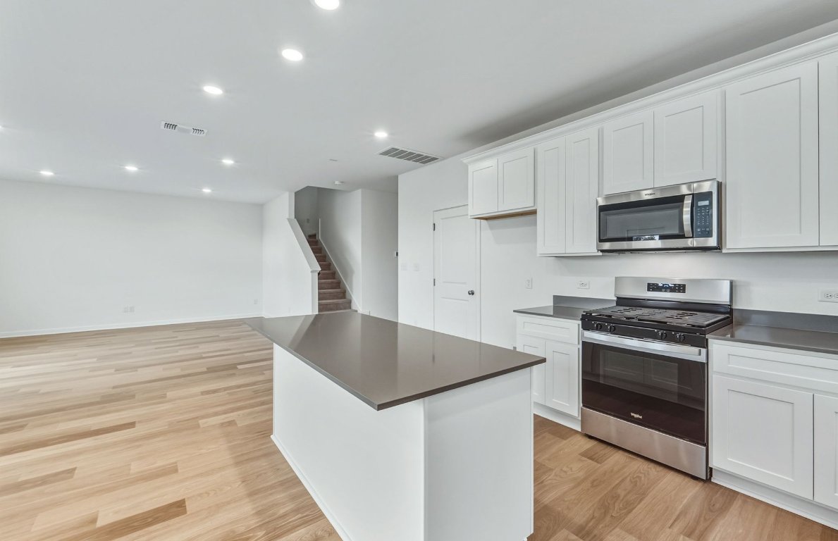 337 Sullivan Way Elgin, TX 78621 - Photo 6 of 25 a kitchen with stainless steel appliances kitchen island granite countertop a stove a sink and a microwave