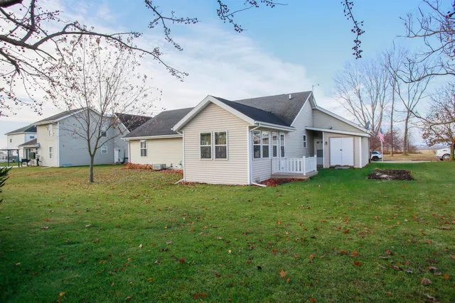 a view of a yard in front of a house with plants and large tree