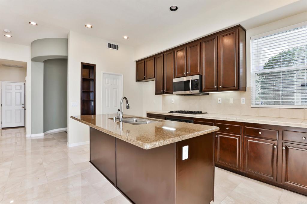11477 Miro Circle San Diego, CA 92131 - Photo 7 of 36 a kitchen with stainless steel appliances granite countertop a sink stove and microwave