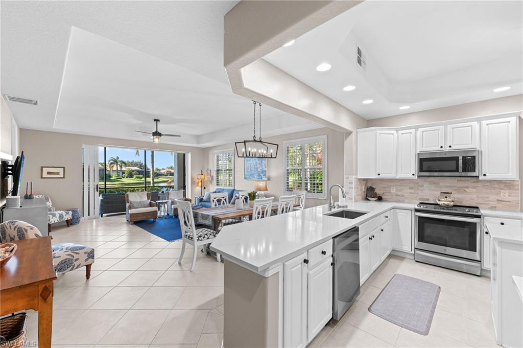 6418 Legacy Circle, Unit 802 Naples, FL 34113 - Photo 46 of 47 a large white kitchen with lots of counter top space a sink stainless steel appliances and cabinets