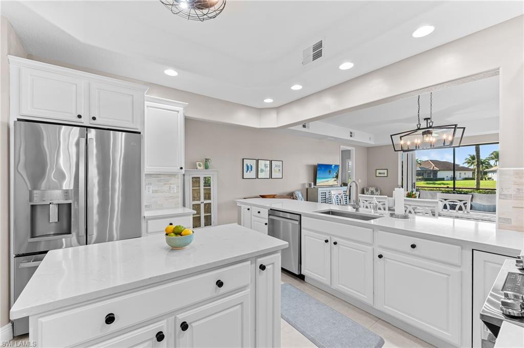 6418 Legacy Circle, Unit 802 Naples, FL 34113 - Photo 7 of 47 a kitchen with stainless steel appliances a sink a stove a refrigerator cabinets and living room view