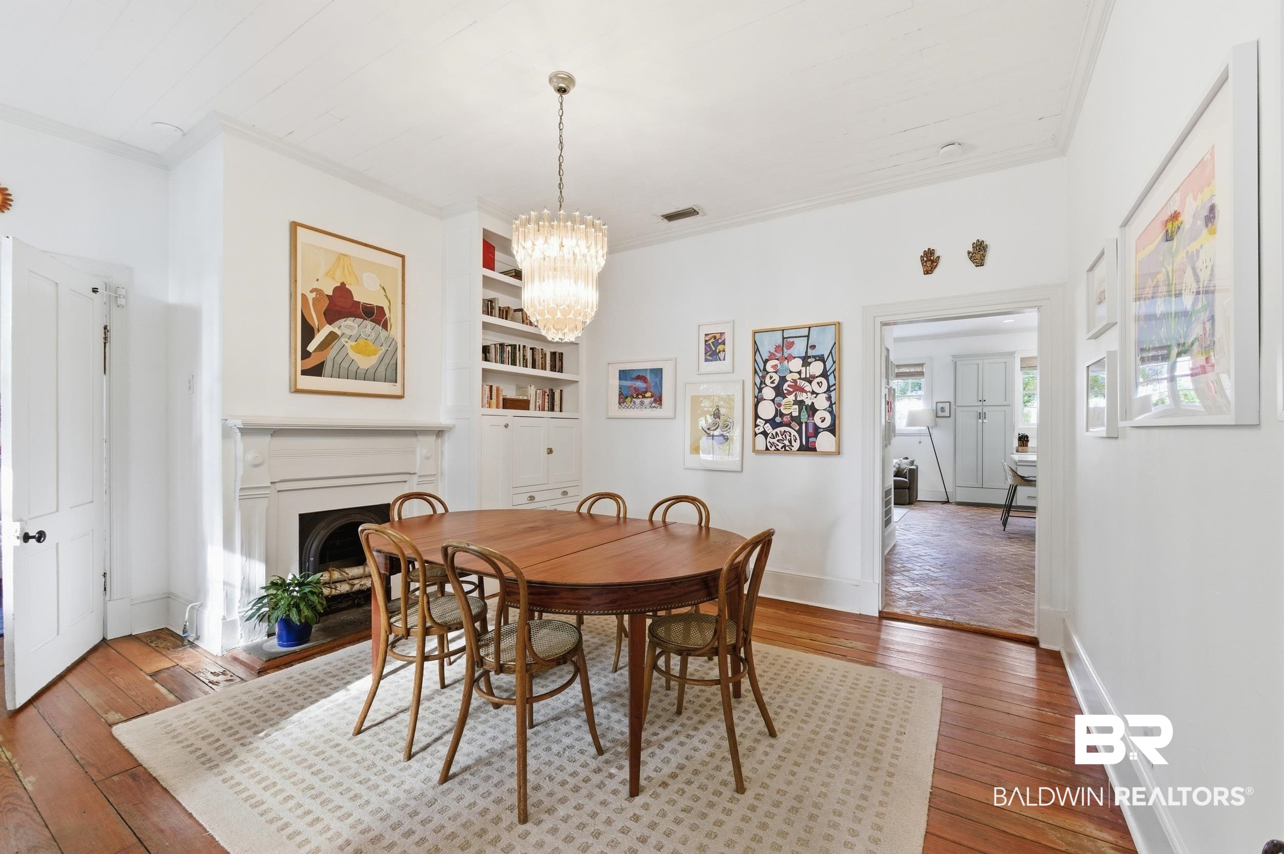350 Charles Street Mobile, AL 36604 - Photo 14 of 52 Dining area featuring hardwood flooring, a decorative fireplace with a mantle, built-in shelving, a chandelier, and a wide doorway