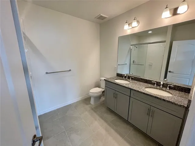 a bathroom with a double vanity sink toilet and mirror