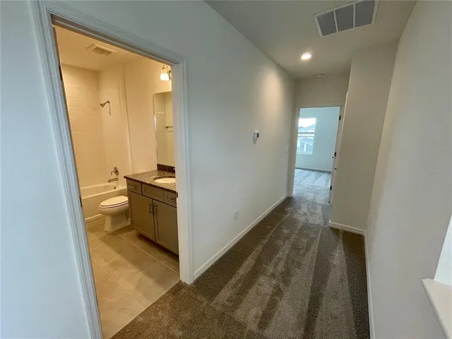 a view of a hallway with bathroom and wooden floor