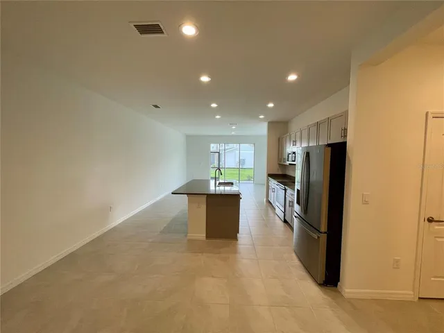 a kitchen with stainless steel appliances kitchen island granite countertop a refrigerator a stove and a sink