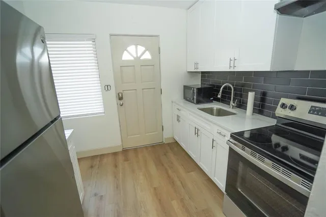 a view of a kitchen with refrigerator and wooden floor