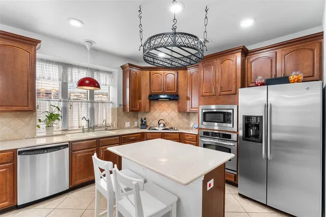 a very nice looking kitchen with granite countertop a stove two chairs and a refrigerator