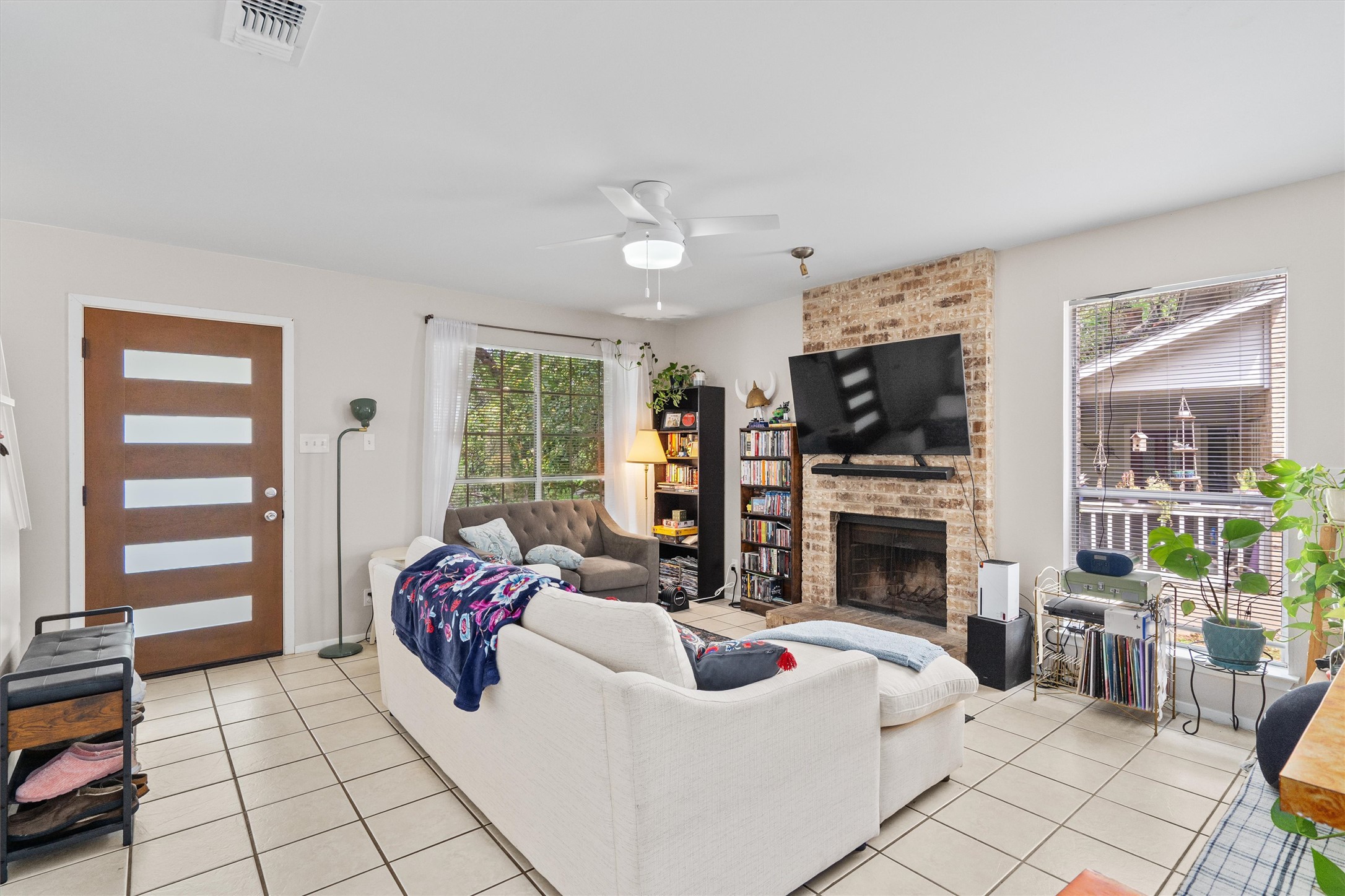 1707 Waterloo Trail Austin, TX 78704 - Photo 28 of 39 Living area featuring a ceiling fan, light tile patterned floors, and a brick fireplace