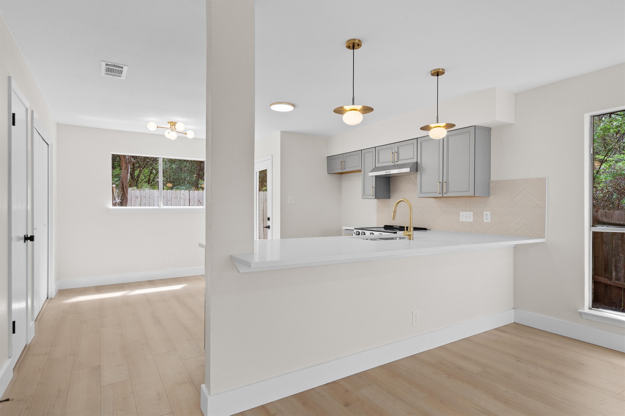 1707 Waterloo Trail Austin, TX 78704 - Photo 9 of 39 Kitchen featuring decorative backsplash, gray cabinets, a peninsula, and light wood-style floors