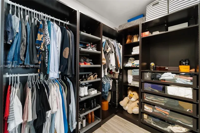 a view of walk in closet with clothes and shoes