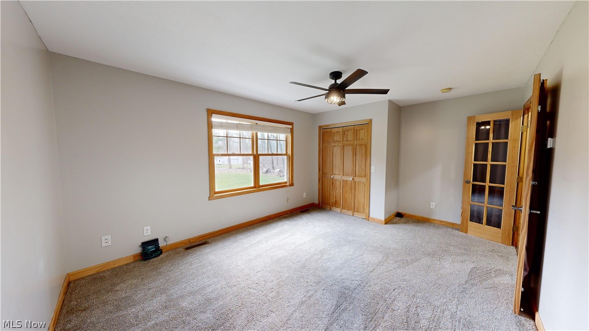 15548 Trask Road Thompson, OH 44086 - Photo 17 of 31 First floor bedroom with ceiling fan, a closet, and light carpet