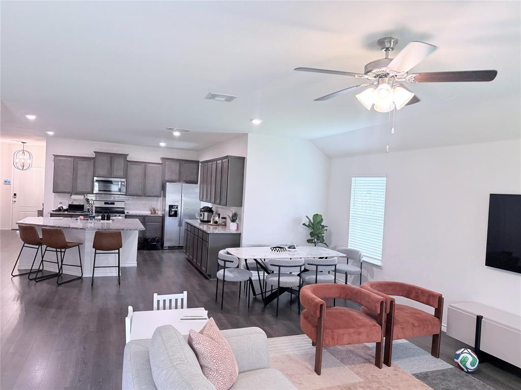 1602 Maple Ridge Drive Princeton, TX 75407 - Photo 9 of 13 Open-concept living space featuring wood-finish flooring, vaulted ceilings, and a ceiling fan with integrated lighting