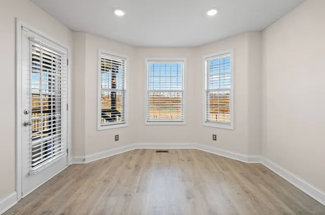 a view of an empty room with a window and wooden floor