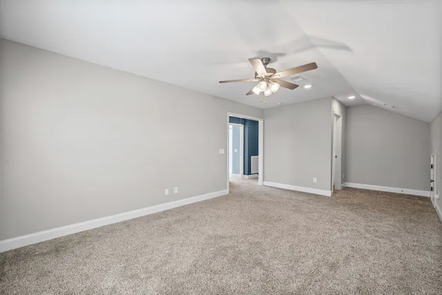 a view of an empty room with a ceiling fan and window