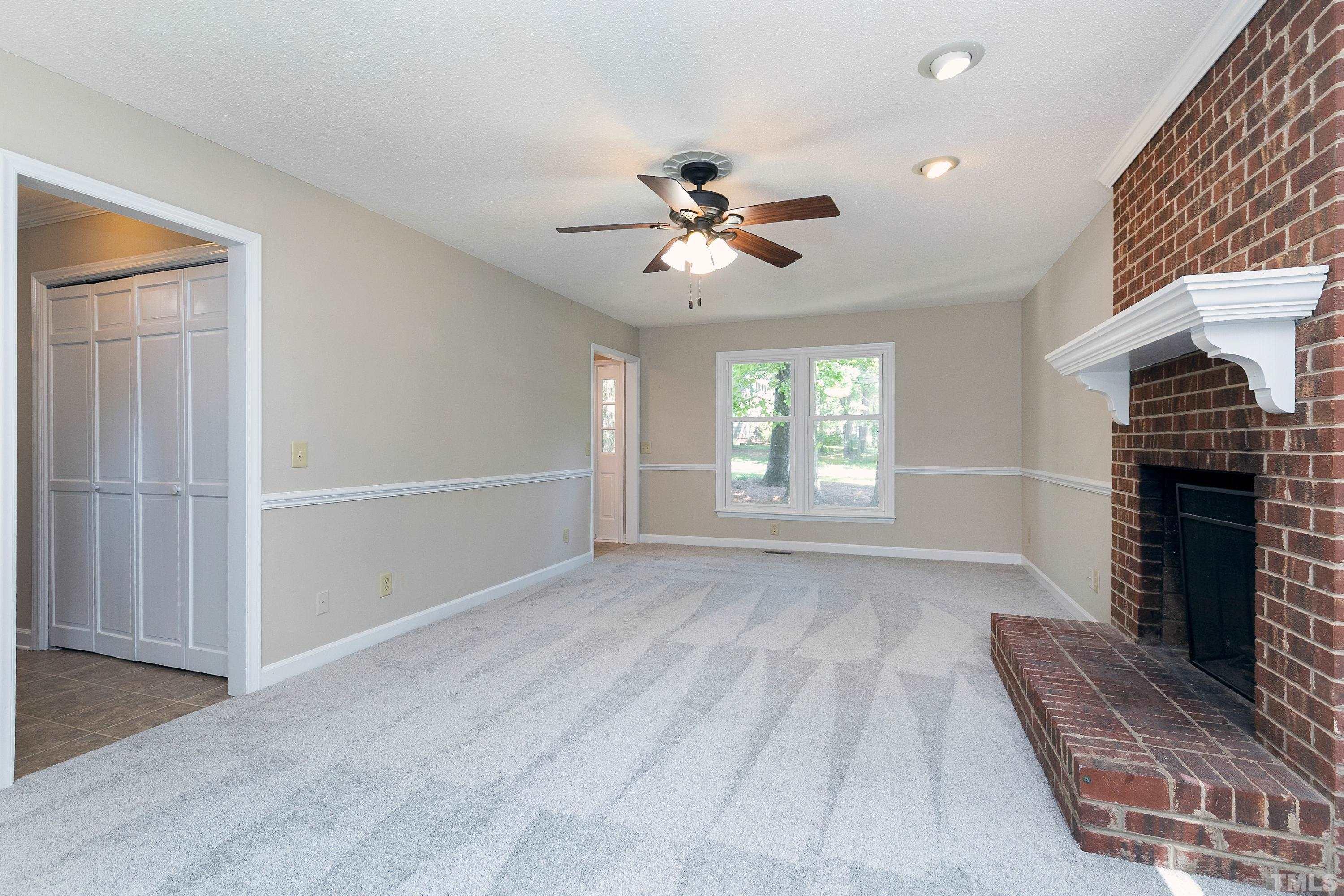 1104 Apache Lane Apex, NC 27502 - Photo 15 of 29 a view of a livingroom with a fireplace a ceiling fan and windows