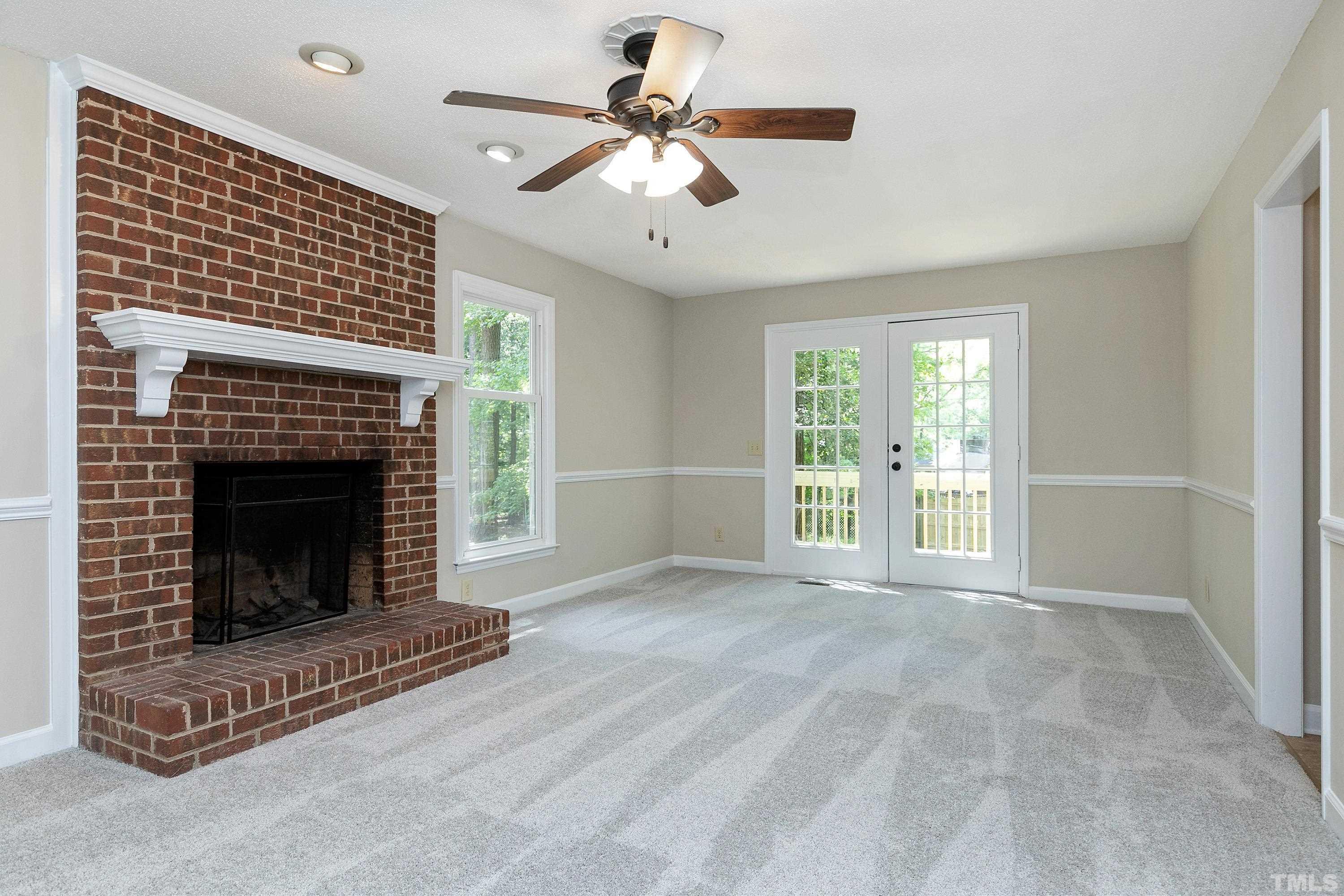 1104 Apache Lane Apex, NC 27502 - Photo 16 of 29 a view of a livingroom with a fireplace a ceiling fan and windows