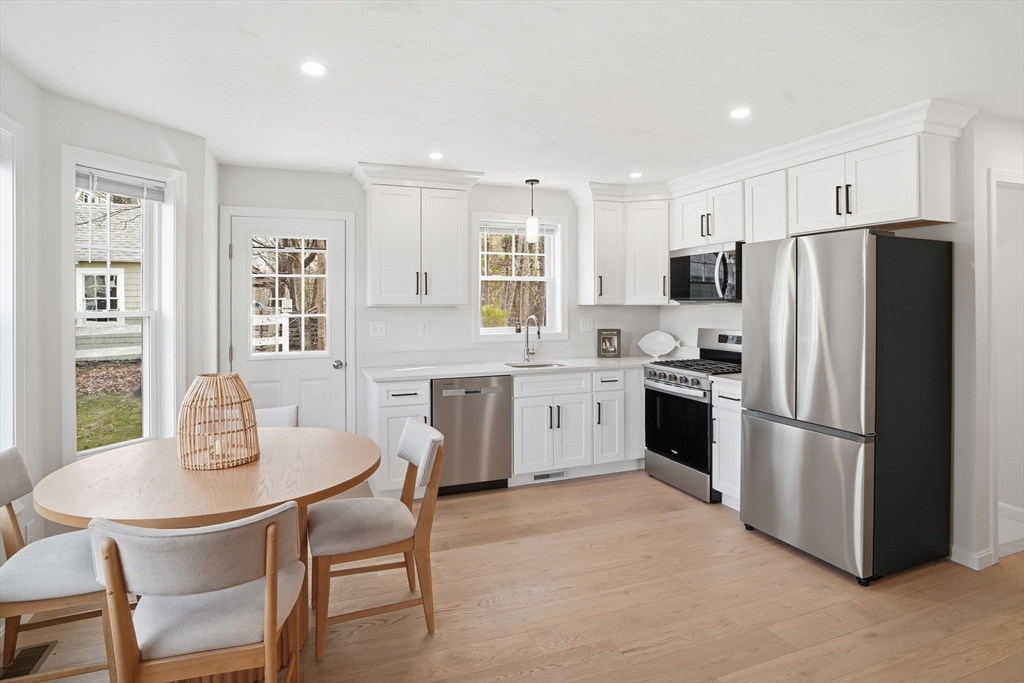 21 Ambrose Way, Unit 21 Shirley, MA 01464 - Photo 6 of 31 a kitchen with stainless steel appliances granite countertop a dining table chairs refrigerator and microwave