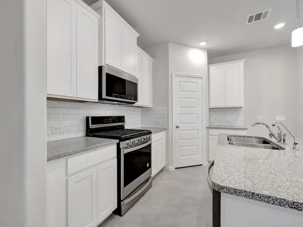 a kitchen with stainless steel appliances granite countertop a sink stove oven and white cabinets