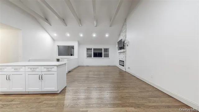 a living room with wooden floors and kitchen view