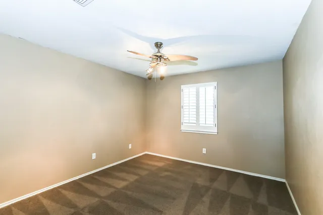 an empty room with windows and ceiling fan