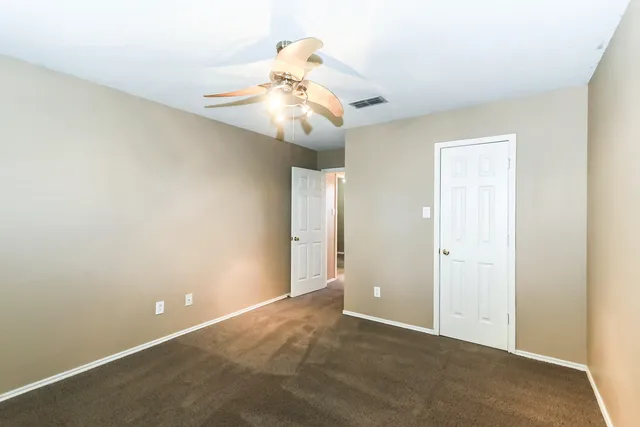 an empty room with a window and a chandelier fan