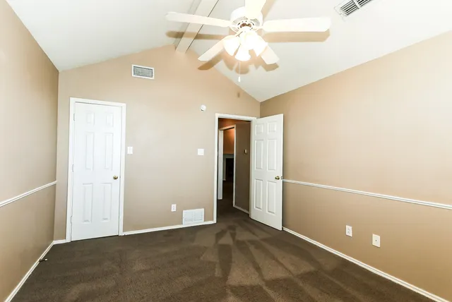 an empty room with a chandelier fan and closet area