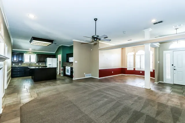 a view of an empty room with a window and kitchen view