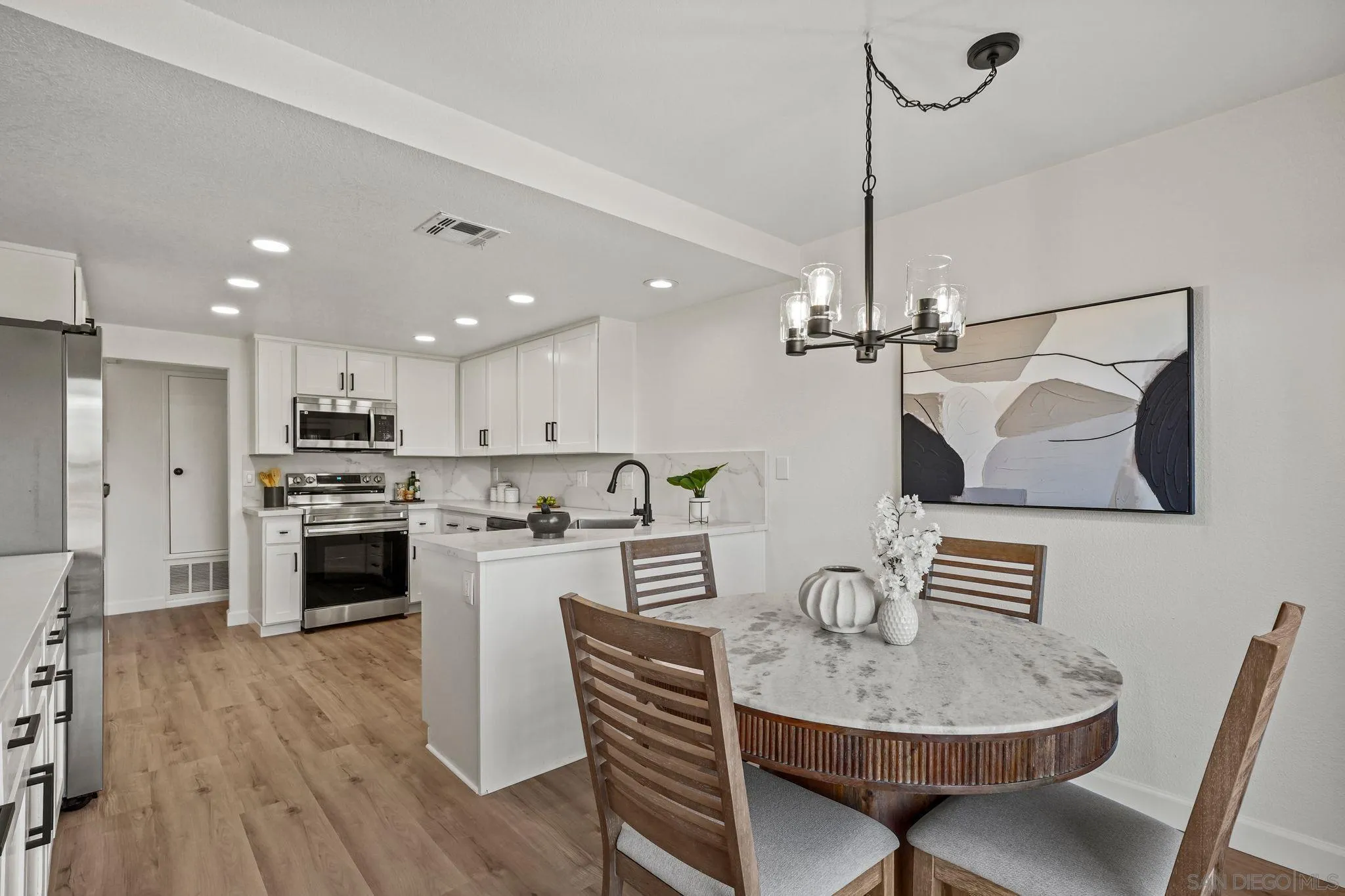 1274 Rue St Moritz San Marcos, CA 92078 - Photo 10 of 39 a kitchen with stainless steel appliances granite countertop a sink dishwasher a stove a refrigerator a microwave oven a dining table and chairs with wooden floor