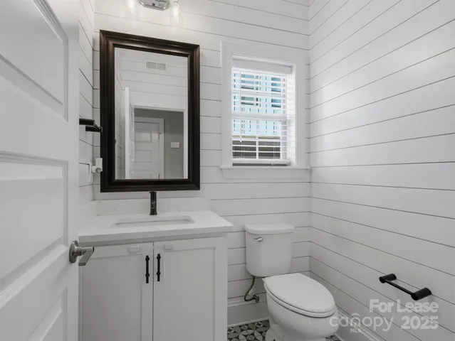 a bathroom with a toilet sink vanity and mirror