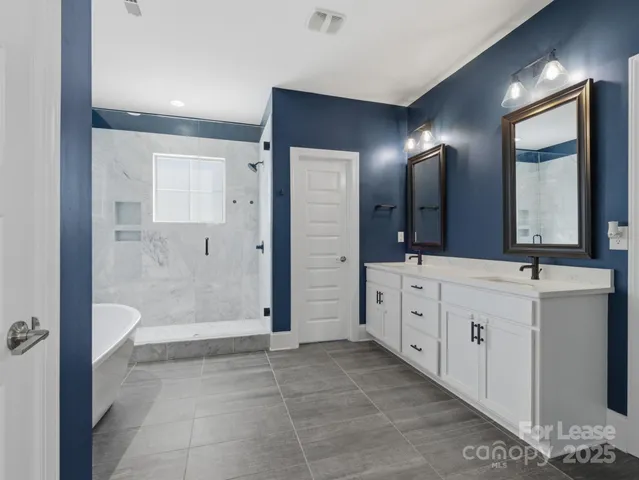 a spacious bathroom with a double vanity sink a large mirror and a shower