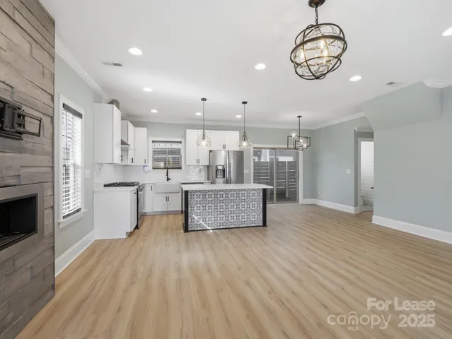 a room with stainless steel appliances wooden floors and kitchen view