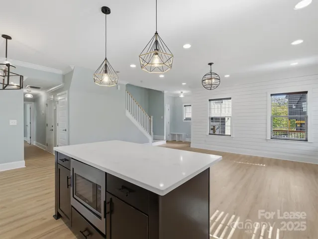 a kitchen with a stove a sink a center island and wooden floor