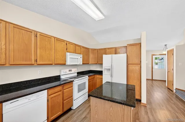a kitchen with granite countertop white cabinets and white appliances