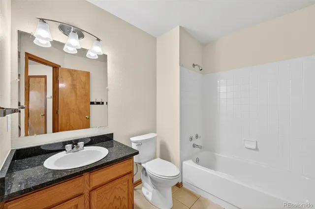 a bathroom with a granite countertop sink a toilet a mirror a bathtub and shower
