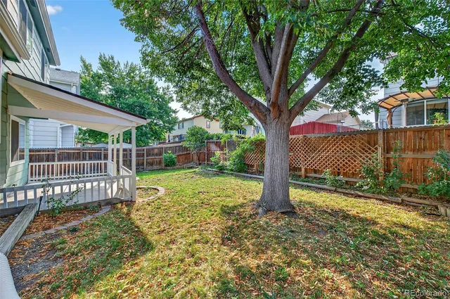 a view of a backyard with wooden fence and a large tree