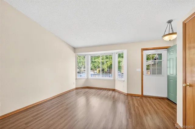 an empty room with wooden floor and windows