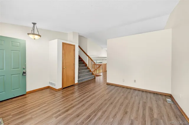 a view of an empty room with wooden floor and stairs