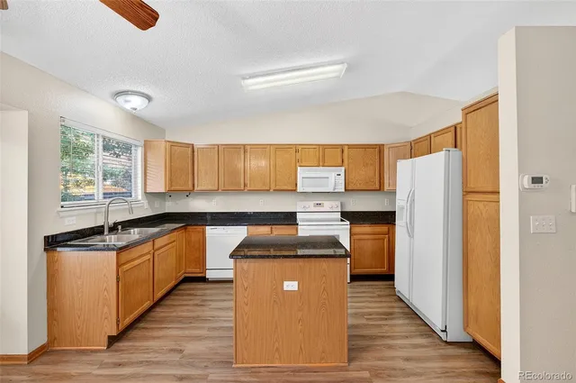 a kitchen with granite countertop a refrigerator and a sink