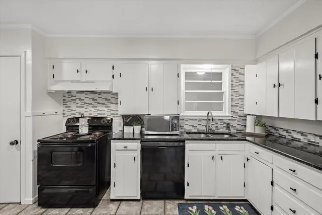 a kitchen with granite countertop a stove sink and cabinets