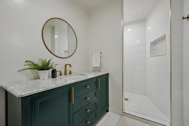a bathroom with a granite countertop sink a mirror and a shower