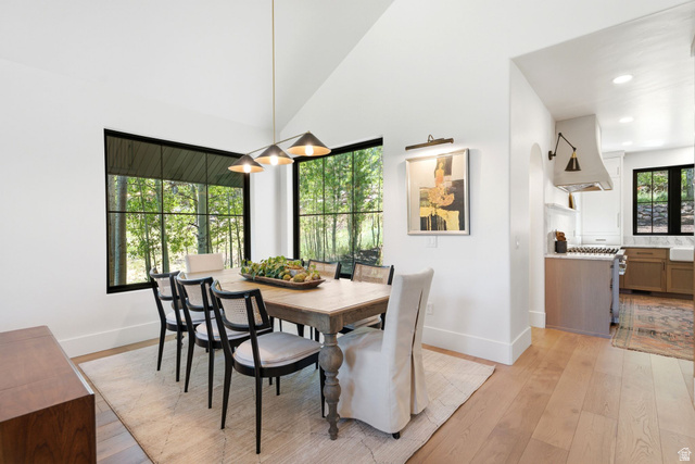 3027 Homestead Road Park City, UT 84098 - Photo 5 of 62 Dining area featuring expansive black-framed windows, vaulted ceilings, wood-finish flooring, and a modern linear chandelier