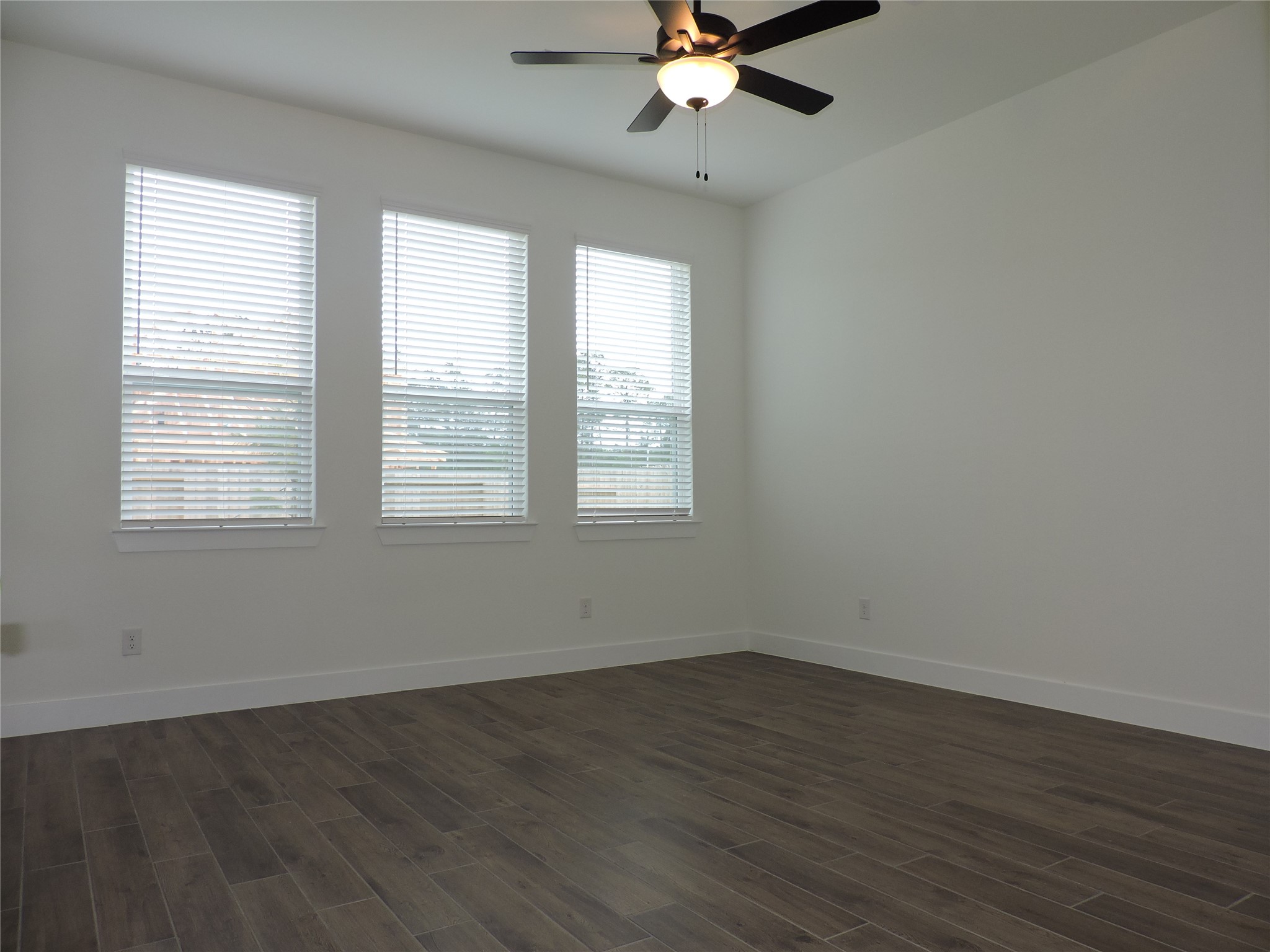 12853 Meadow Wind Way Conroe, TX 77302 - Photo 18 of 34 Primary bedroom suite located on the first floor, light and bright with wood look tile flooring, ceiling fans in all bedrooms.