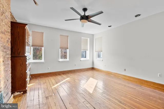 a view of empty room with wooden floor and fan