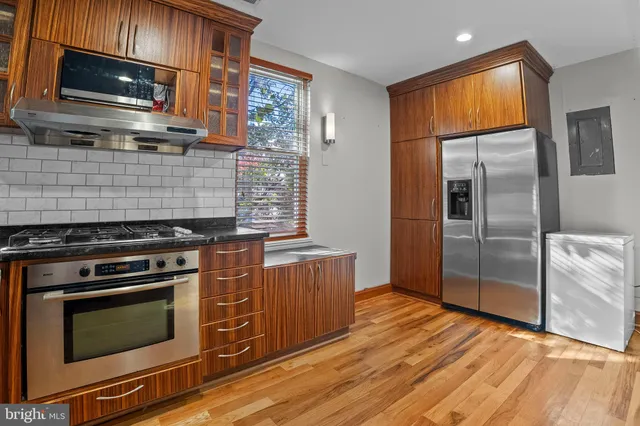 a kitchen with stainless steel appliances wooden cabinets and a stove top oven
