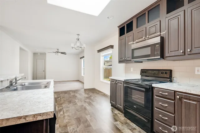 a kitchen with stainless steel appliances granite countertop a stove a sink and a microwave