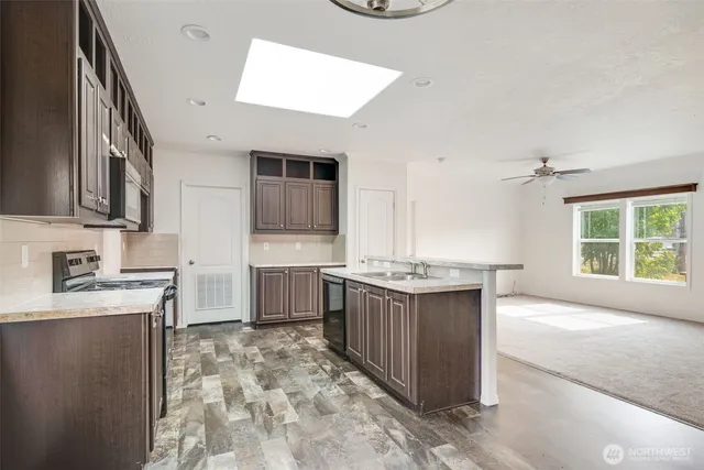 a large kitchen with kitchen island granite countertop a sink and a stove top oven