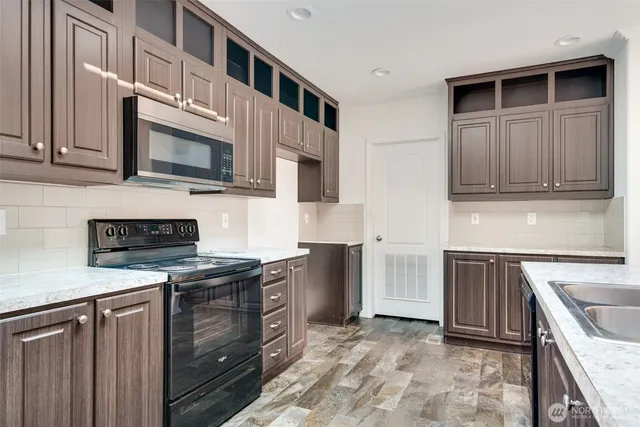 a kitchen with stainless steel appliances granite countertop a stove a sink and a microwave